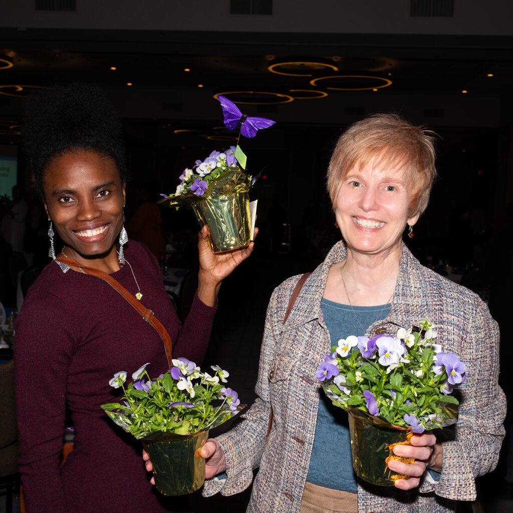 Two women holding plants at an event